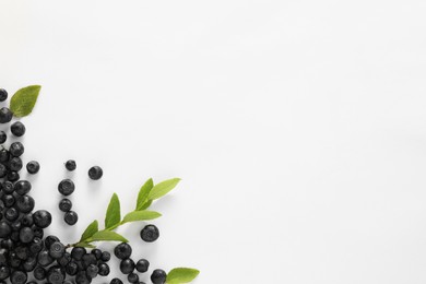 Photo of Ripe bilberries and sprig with leaves on white background, flat lay. Space for text