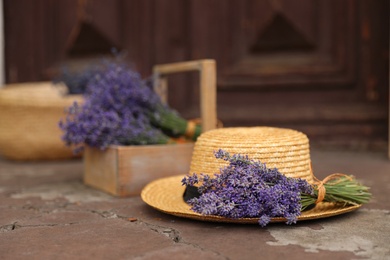 Beautiful lavender flowers and straw hat near building outdoors