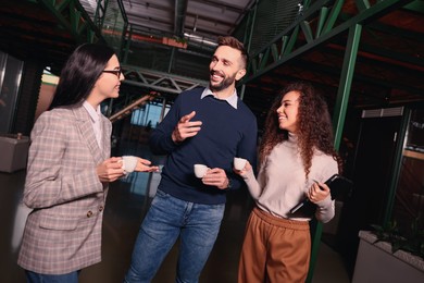 Photo of Group of coworkers talking during coffee break in office