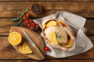 Photo of Chicken with orange slices and other ingredients on wooden table, flat lay