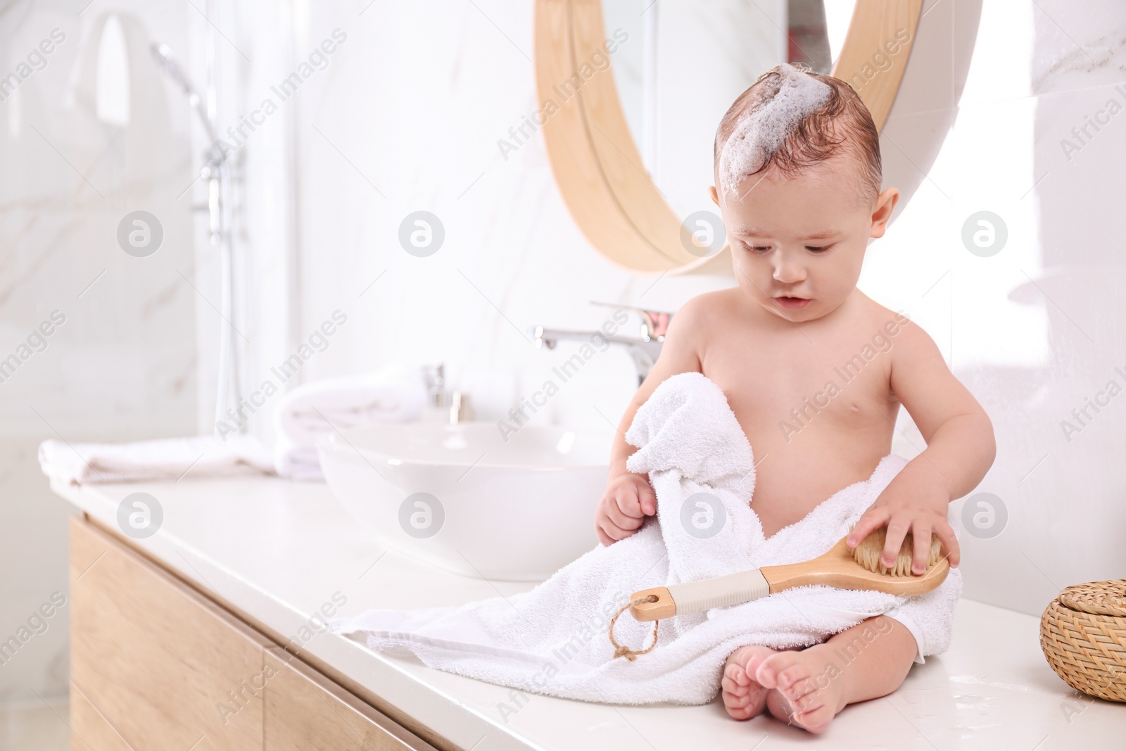 Photo of Cute little baby sitting on countertop in bathroom