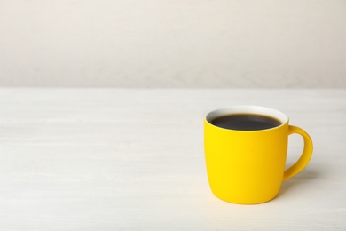 Photo of Yellow ceramic cup with hot aromatic coffee on table