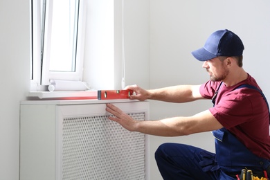 Handyman in uniform working with building level indoors. Professional construction tools