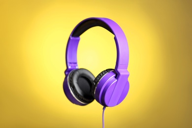 Stylish headphones with pads on color background