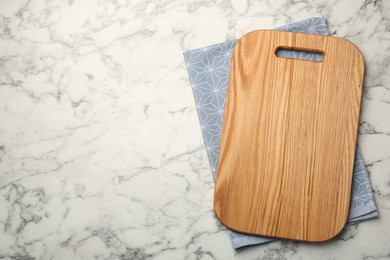Wooden cutting board and napkin on white marble table, top view. Space for text