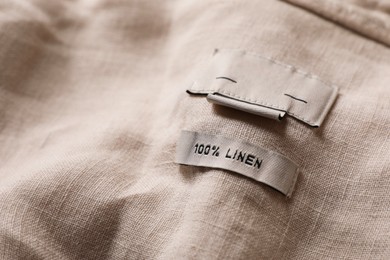 Photo of Clothing label on beautiful beige garment, closeup