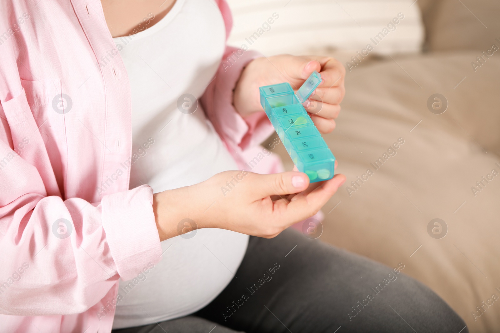 Photo of Pregnant woman holding box with pills indoors, closeup