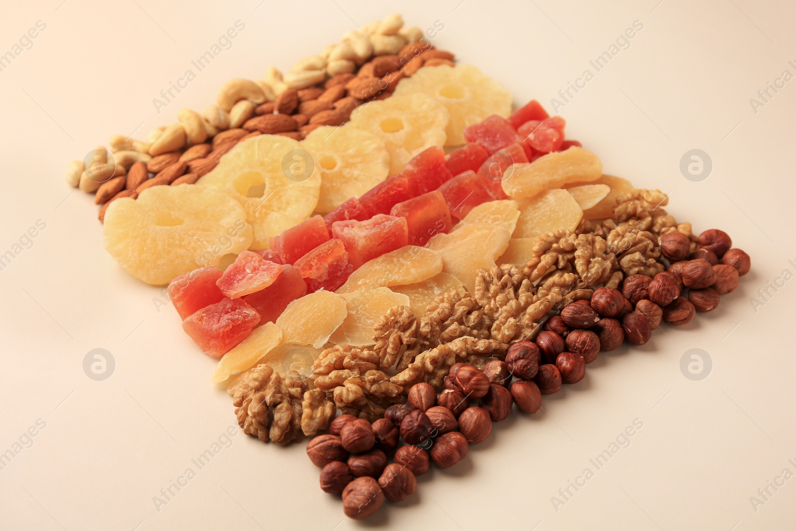 Photo of Different tasty nuts and dried fruits on beige background