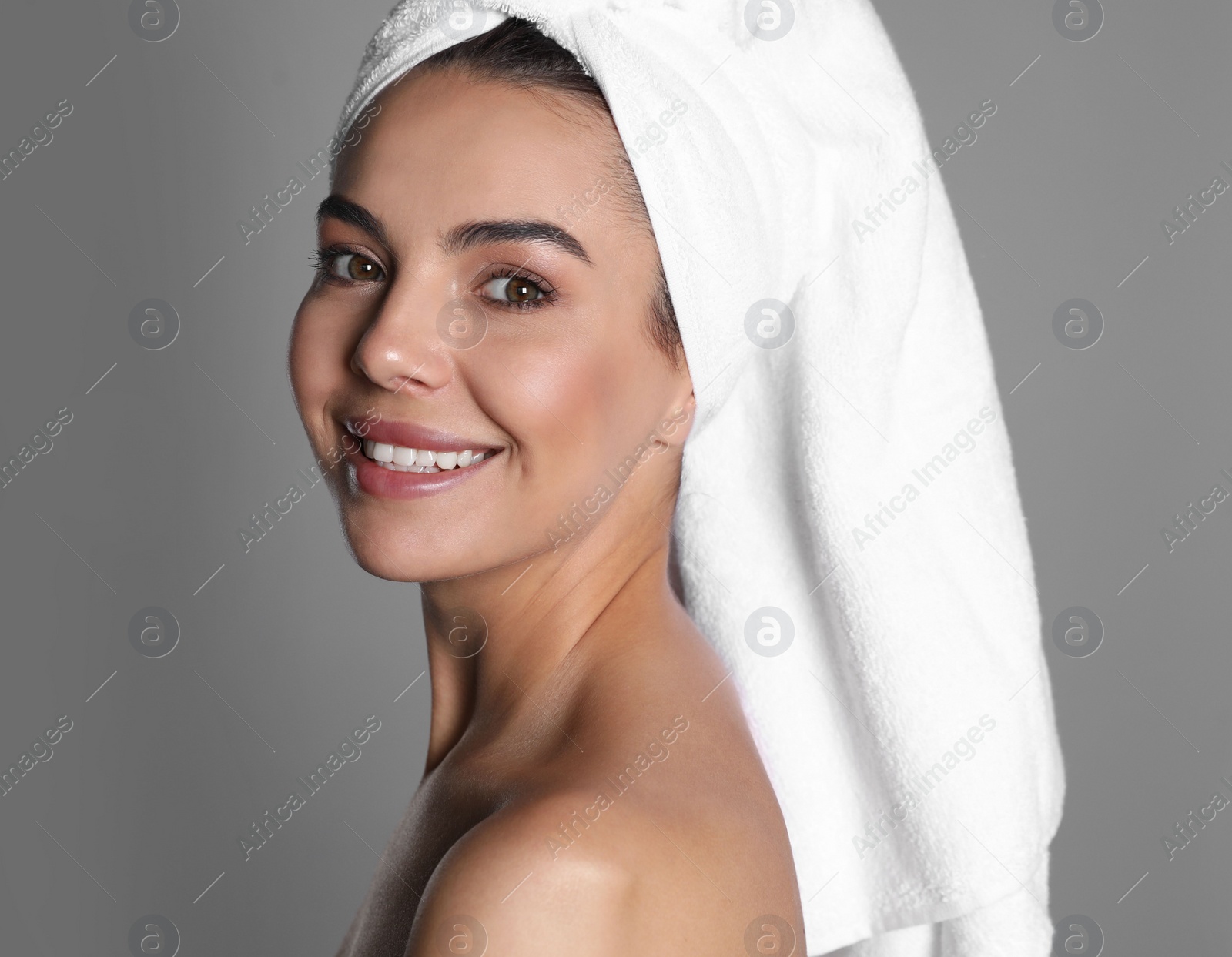 Photo of Beautiful young woman with towel on head against grey background