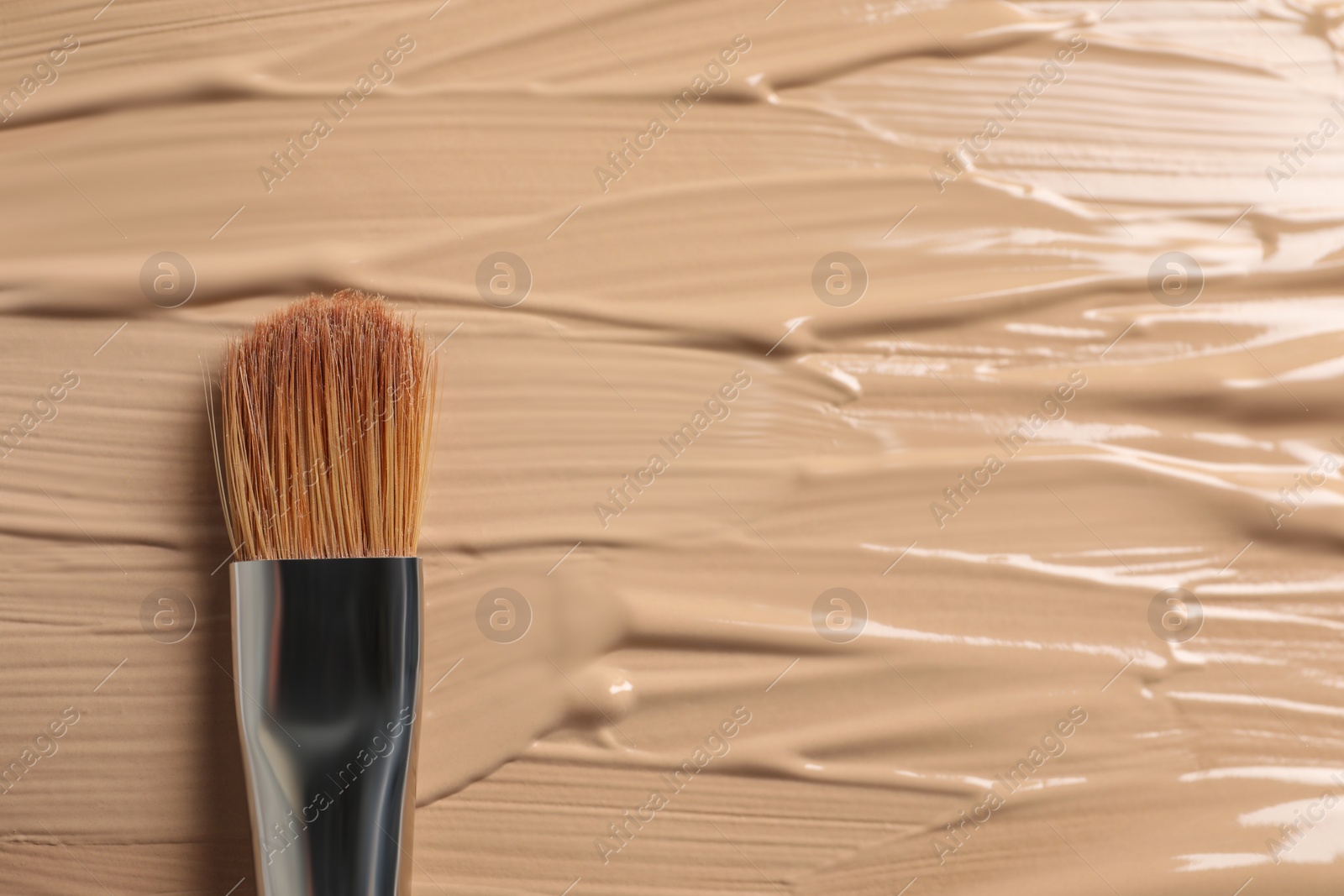 Photo of Skin foundation and makeup brush as background, closeup