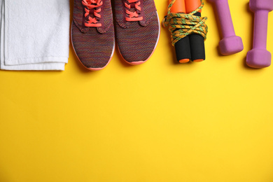 Photo of Flat lay composition with fitness equipment and shoes on yellow background, space for text
