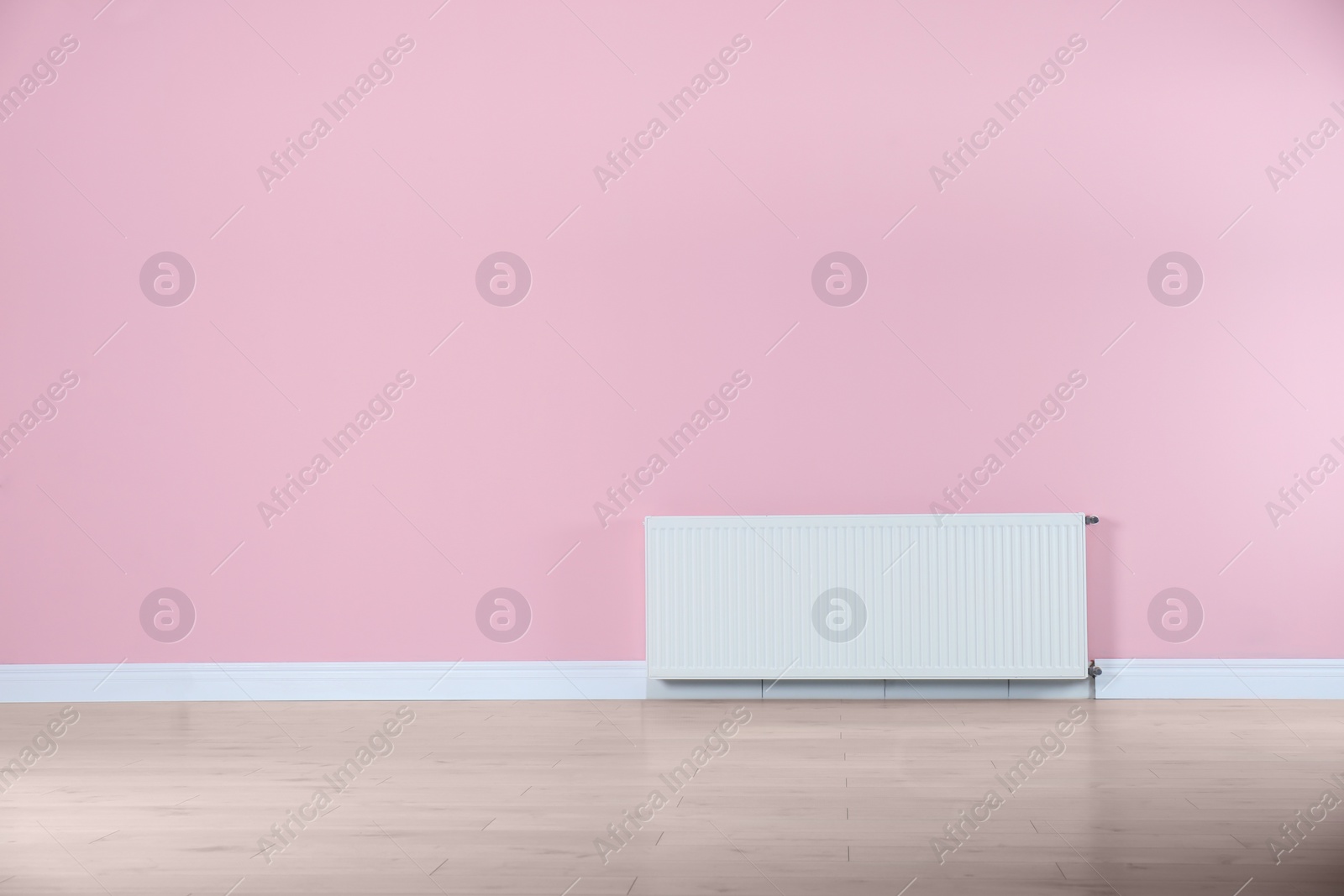 Photo of Modern radiator on color wall with space for text. Central heating system