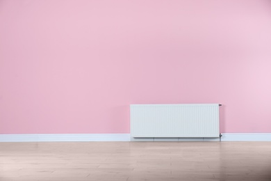 Modern radiator on color wall with space for text. Central heating system