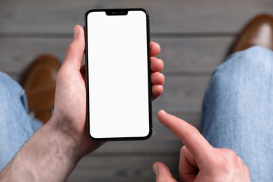 Photo of Man holding smartphone with blank screen indoors, top view. Mockup for design