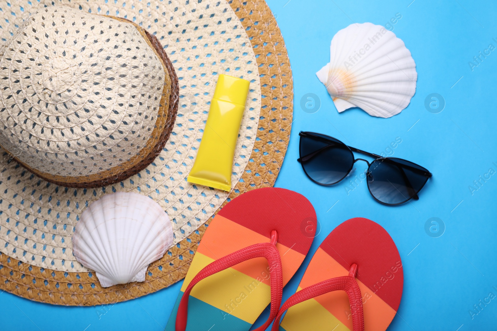 Flat lay composition with sunscreen and beach accessories on light blue background Photo of Flat lay composition with sunscreen and beach accessories on light blue background
