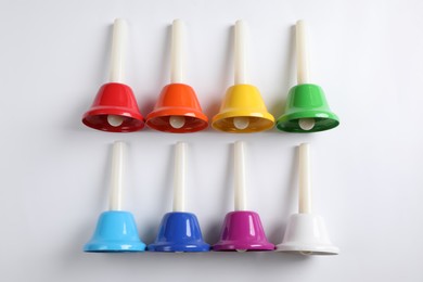 Photo of Set of bright metal hand bells on white background, top view. Montessori musical toy