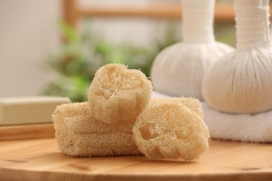 Photo of Loofah sponges on wooden table indoors, closeup