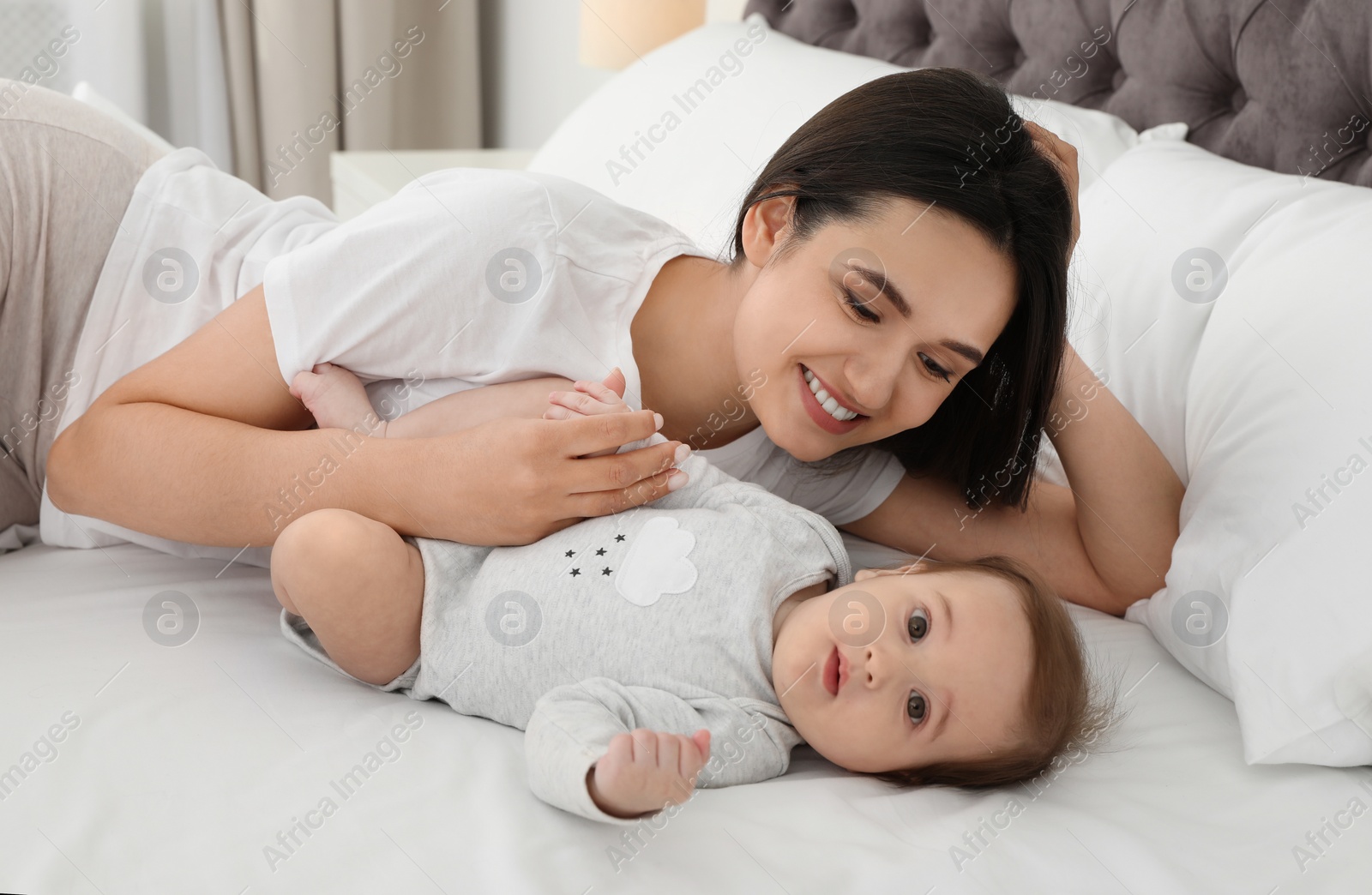 Photo of Portrait of mother with her cute baby lying on bed indoors