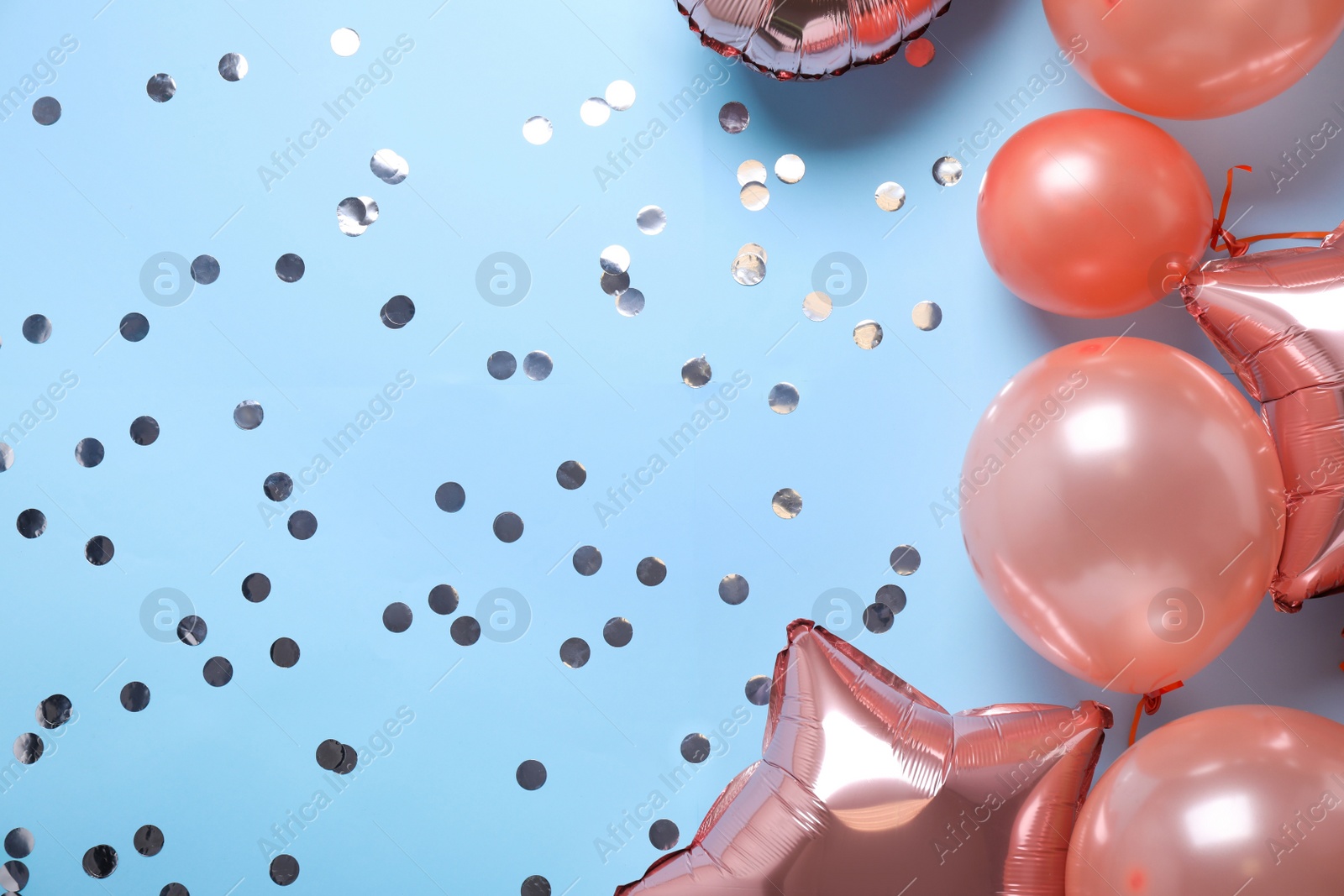 Photo of Colorful balloons and confetti on light blue background, flat lay. Space for text