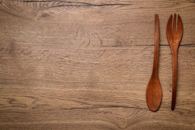 Wooden spoon and fork on table, flat lay with space for text. Cooking utensils