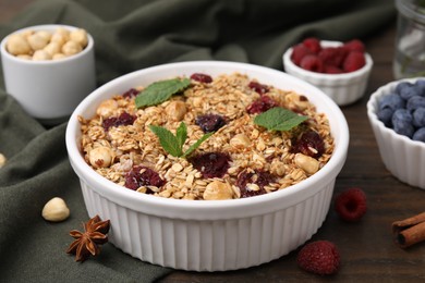 Photo of Tasty baked oatmeal with berries and nuts on wooden table, closeup