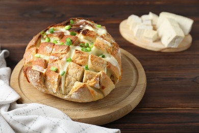 Photo of Freshly baked bread with tofu cheese and green onions on wooden table. Space for text