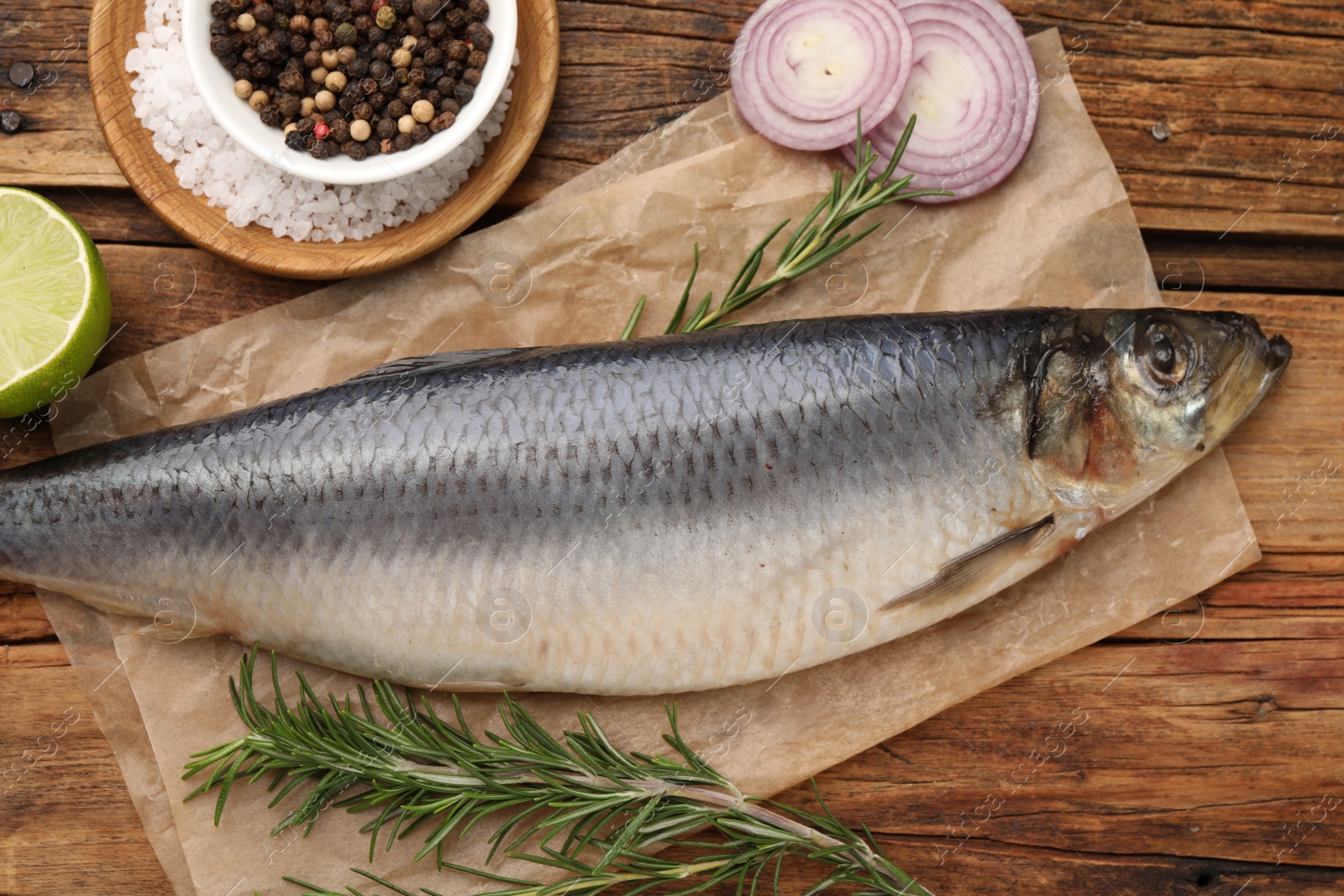 Photo of Delicious salted herring and ingredients on wooden table, flat lay