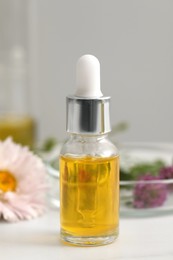 Bottle of cosmetic oil on white table in laboratory, closeup