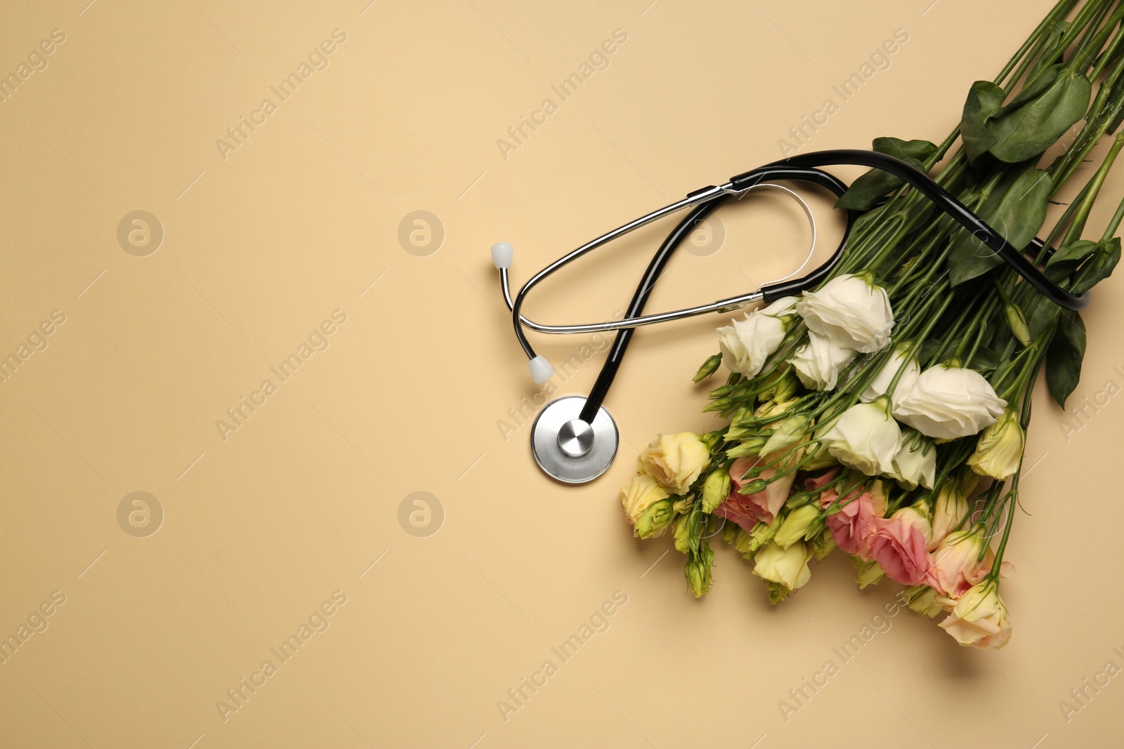 Photo of Stethoscope and flowers on dark beige background, flat lay with space for text. Happy Doctor's Day
