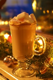 Glass of delicious hot cocoa with marshmallows and Christmas decoration on windowsill