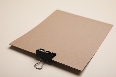 Photo of Sheet of brown paper with clip on beige background