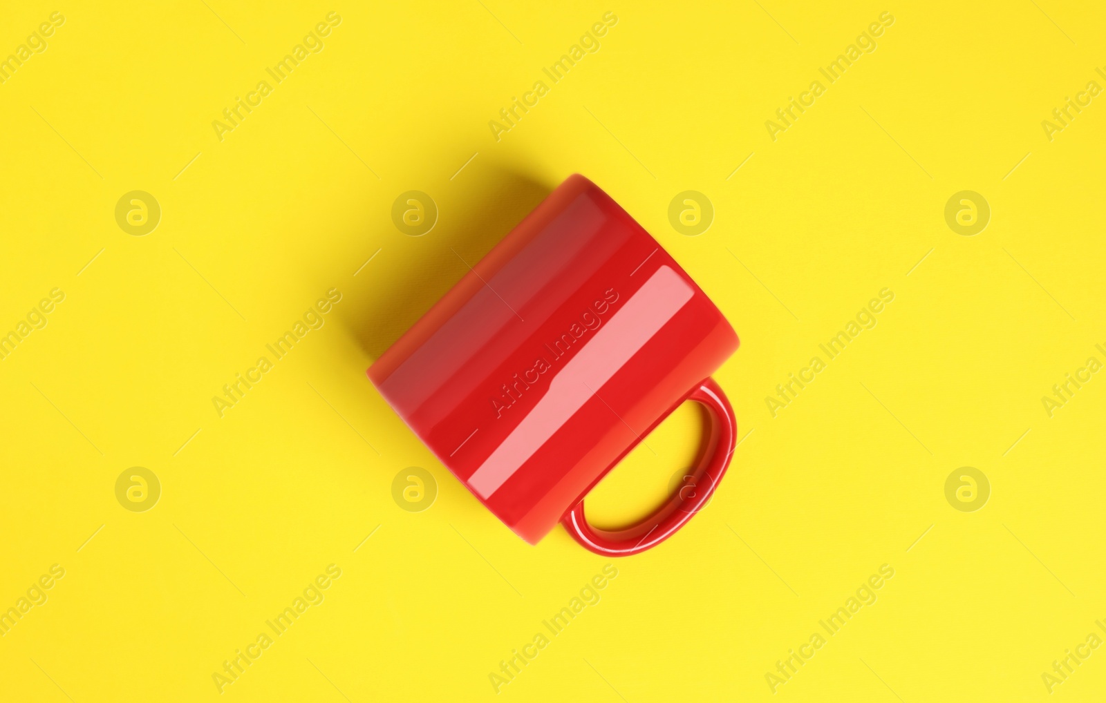 One red ceramic mug on yellow background, top view Photo of One red ceramic mug on yellow background, top view