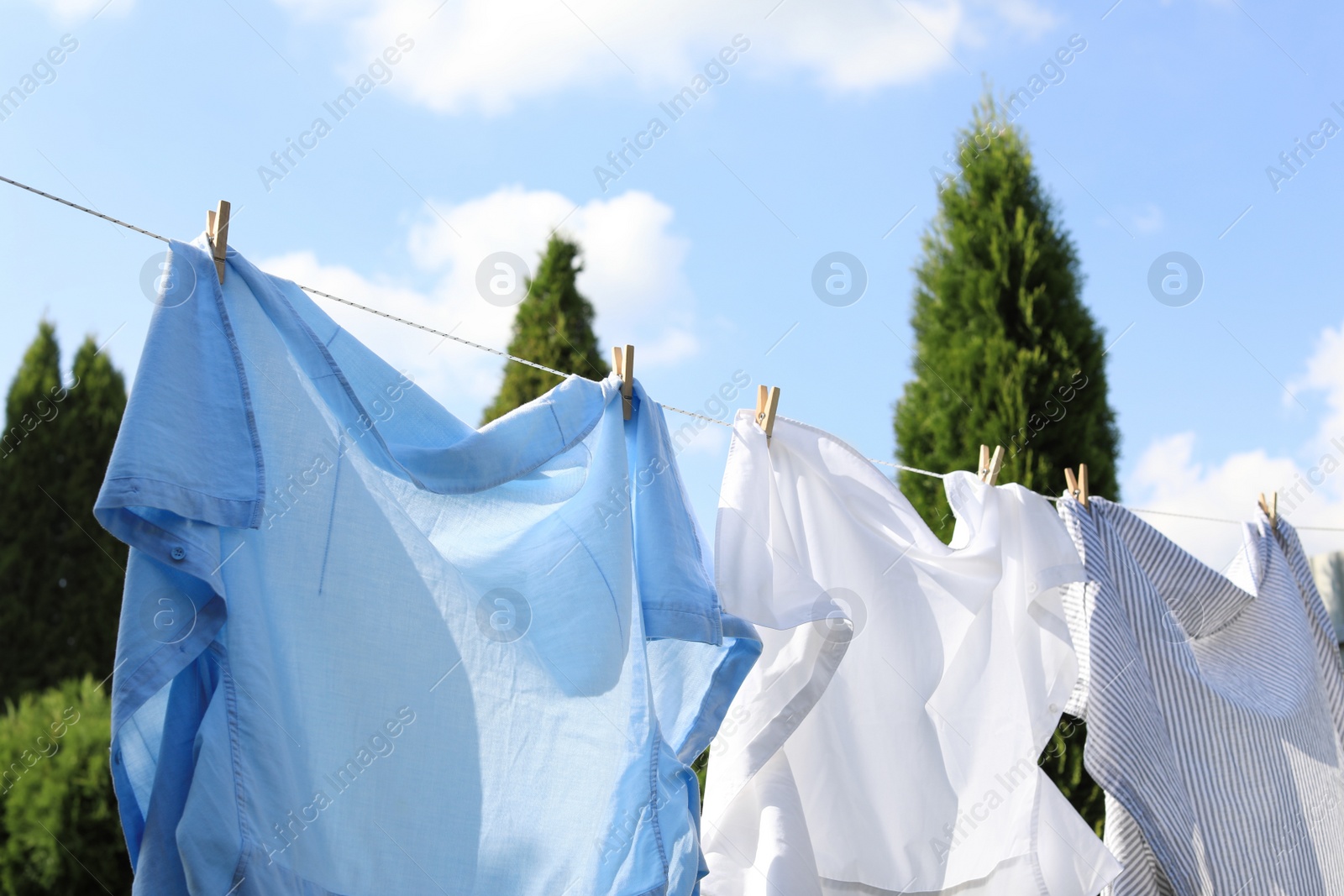 Photo of Clean clothes hanging on washing line outdoors. Drying laundry