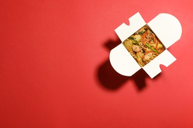Photo of Box of noodle wok on red background, top view. Space for text