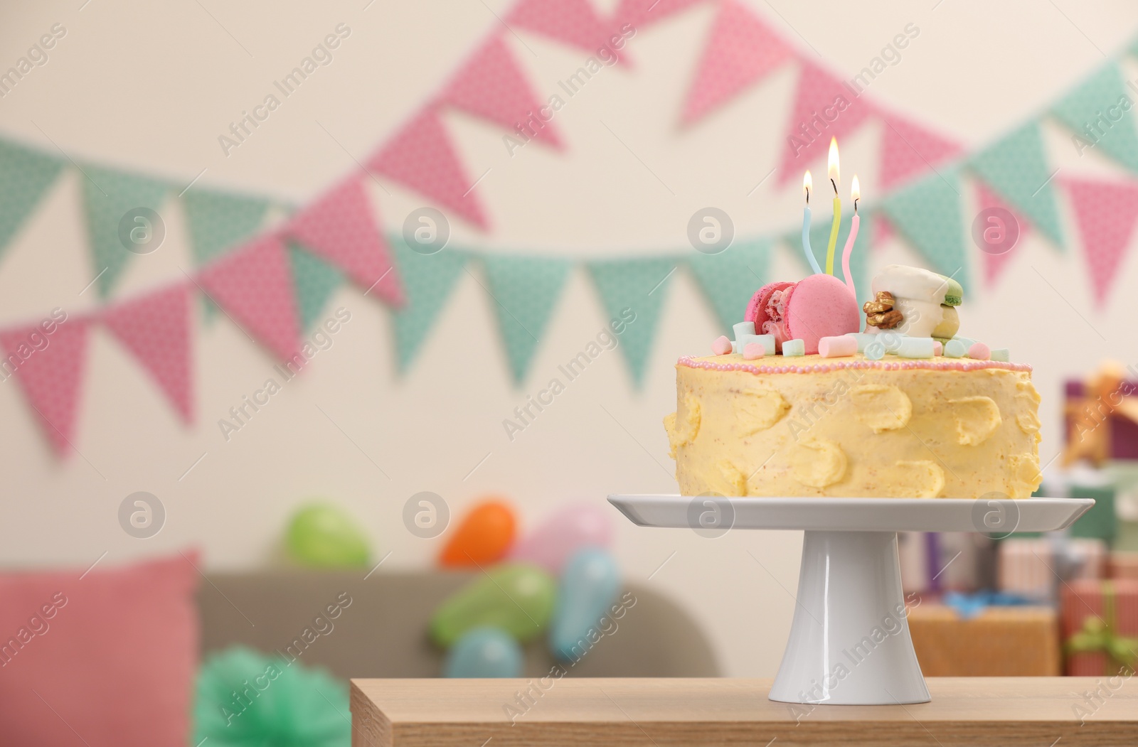 Photo of Delicious cake decorated with macarons and marshmallows on wooden table in festive room, space for text