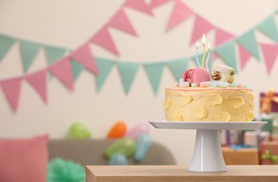 Photo of Delicious cake decorated with macarons and marshmallows on wooden table in festive room, space for text