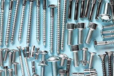 Many different fasteners on light blue background, flat lay