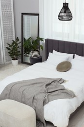 Photo of Large comfortable bed and beautiful houseplants in room. Bedroom interior