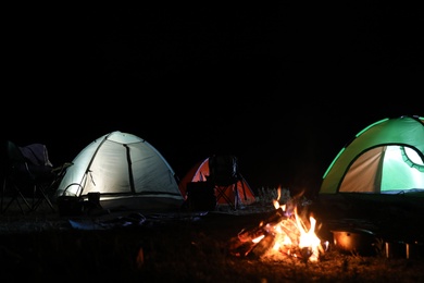 Bonfire near camping tents outdoors at night