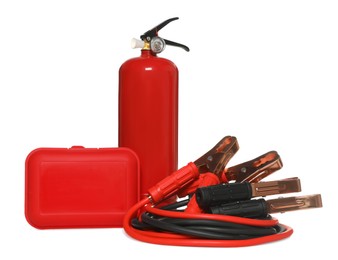 Photo of Red fire extinguisher, first aid kit and battery jumper cables on white background. Car safety