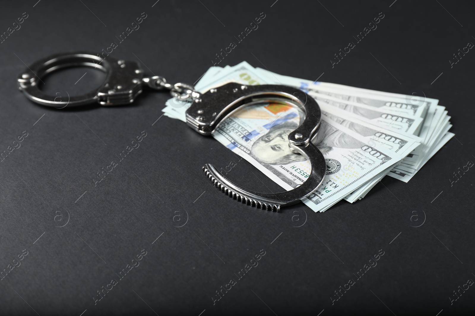 Photo of Dollars and metal handcuffs on grey table