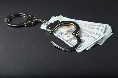 Dollars and metal handcuffs on grey table