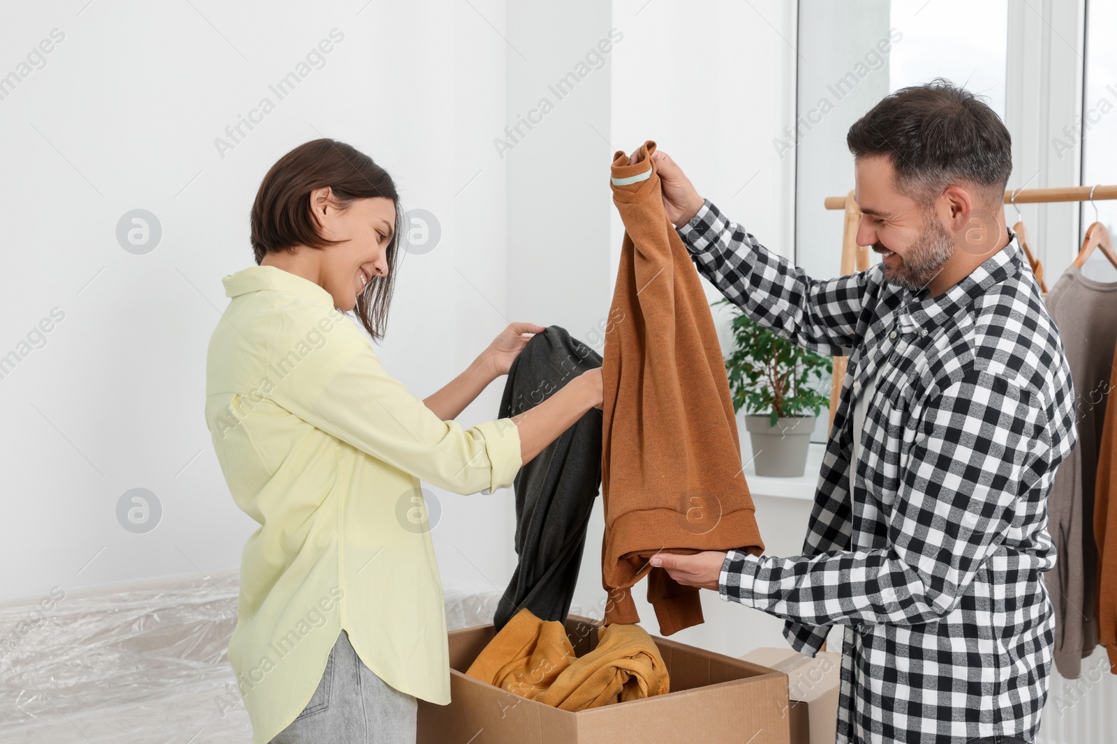 Photo of Happy couple unpacking box in new apartment. Moving day