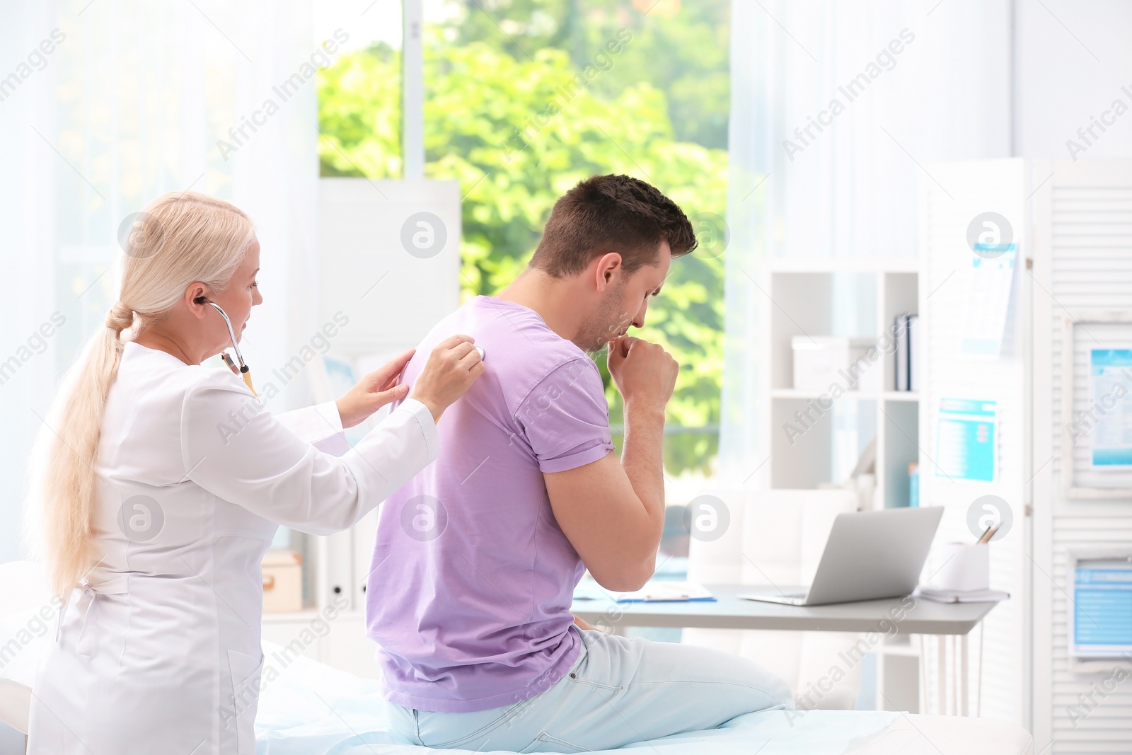 Photo of Doctor examining coughing young man at clinic