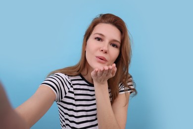 Beautiful woman taking selfie on light blue background