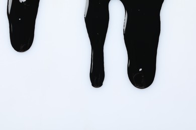 Black glossy oil flowing on white background