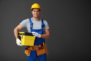 Photo of Handsome carpenter with tool box on dark background. Space for text