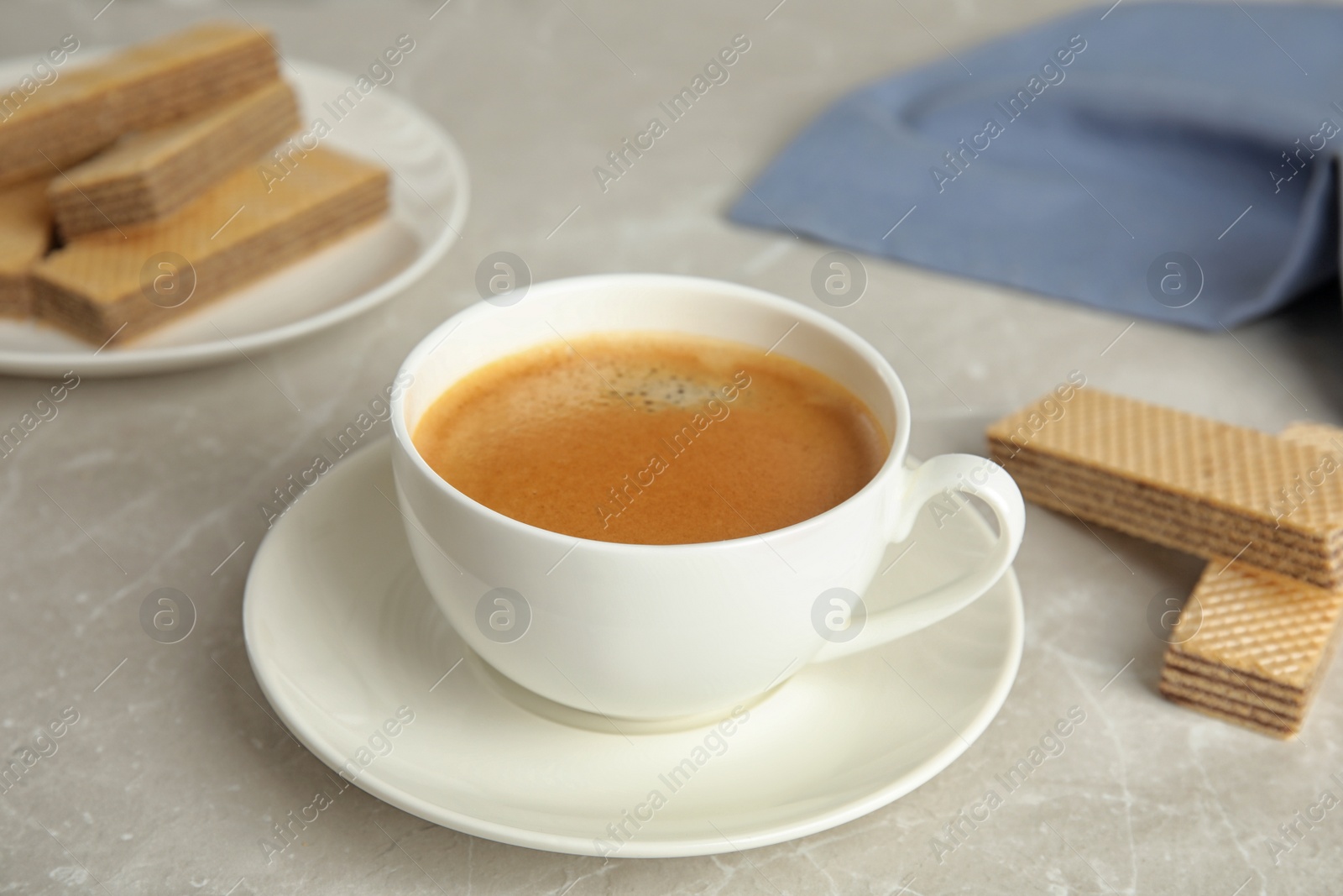 Photo of Delicious coffee and wafers for breakfast on grey marble table