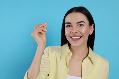 Photo of Young woman snapping fingers on light blue background