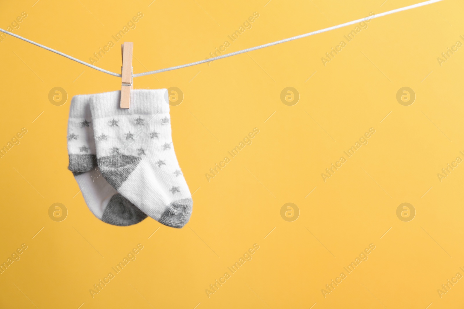 Photo of Small socks hanging on washing line against color background, space for text. Baby accessories